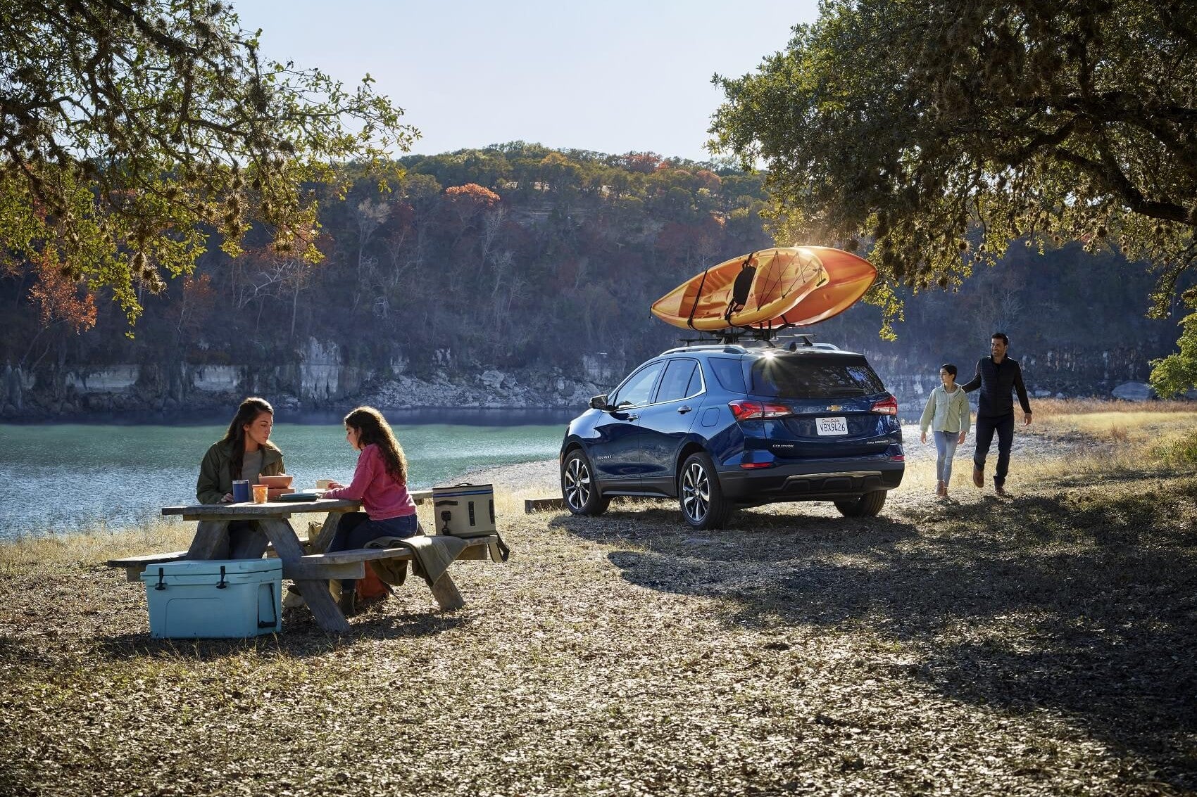 family camping with a chevy blazer. the blazer has an orange kayak on top and is parked in front of a quarry