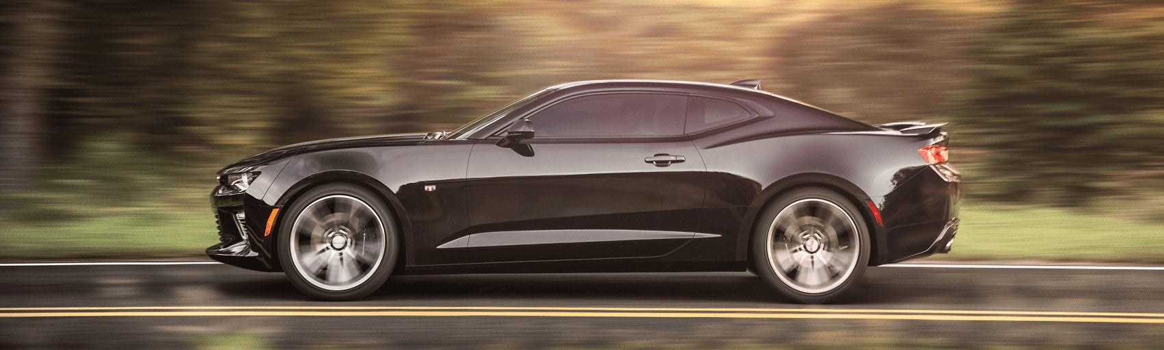 black used chevy camaro driving fast on rural road