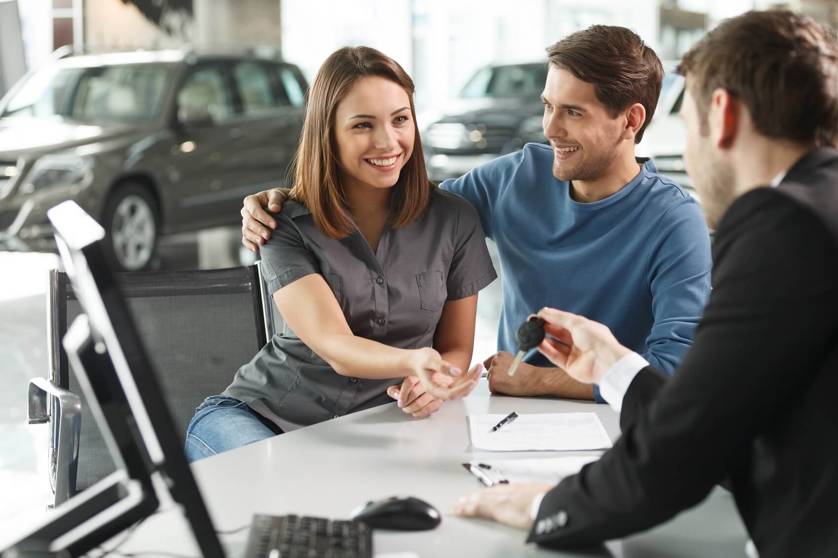 smiling couples receive car keys to their leased car from chevy finance officer