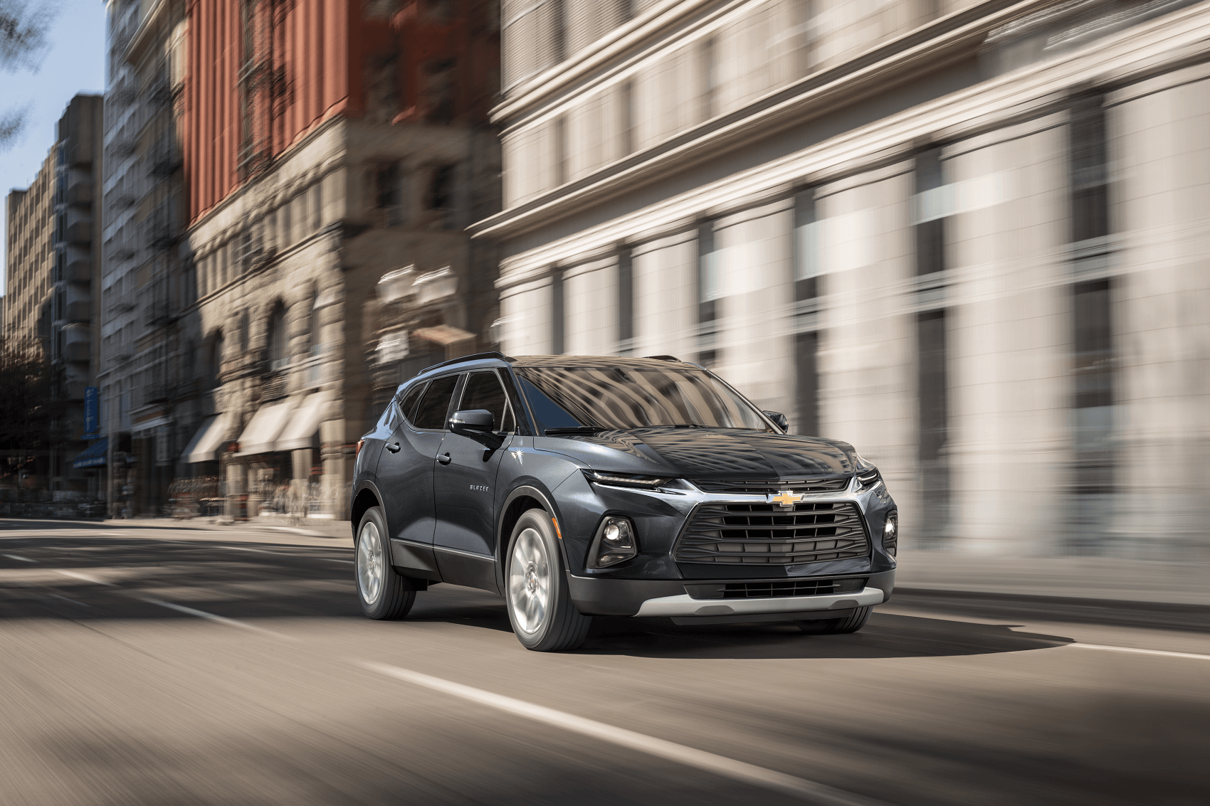 used blue chevy blazer driving on downtown city street