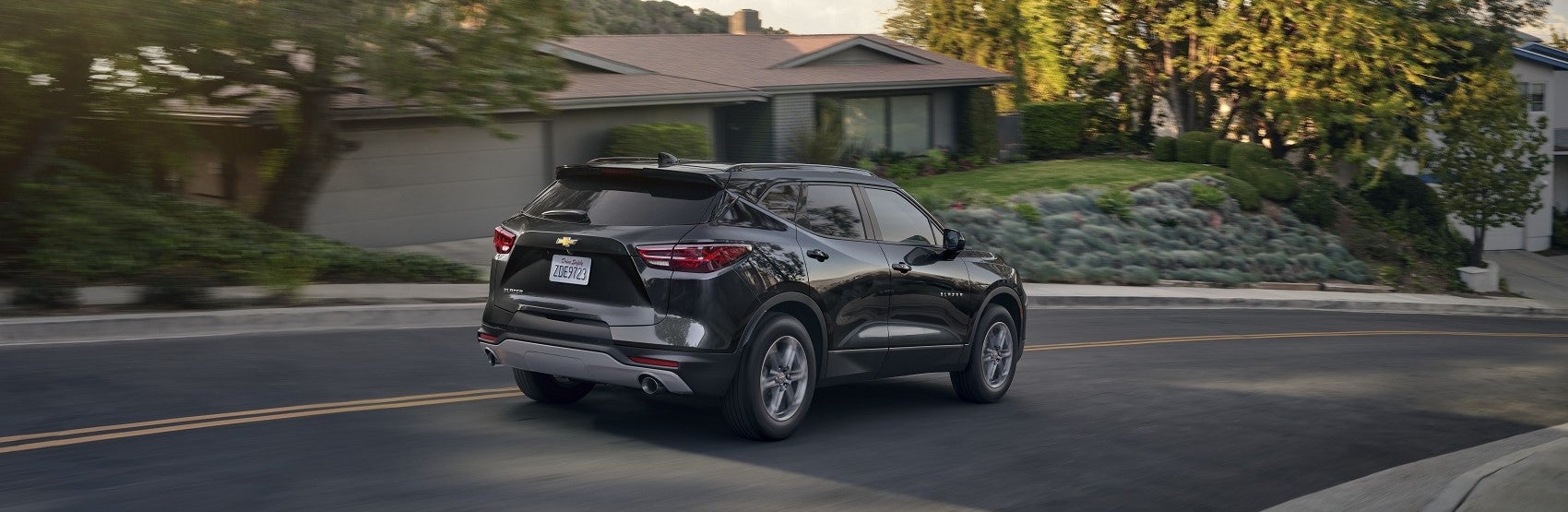 black chevy blazer driving down neighborhood street