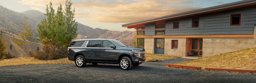 blue chevy suburban park out in front of mountain house